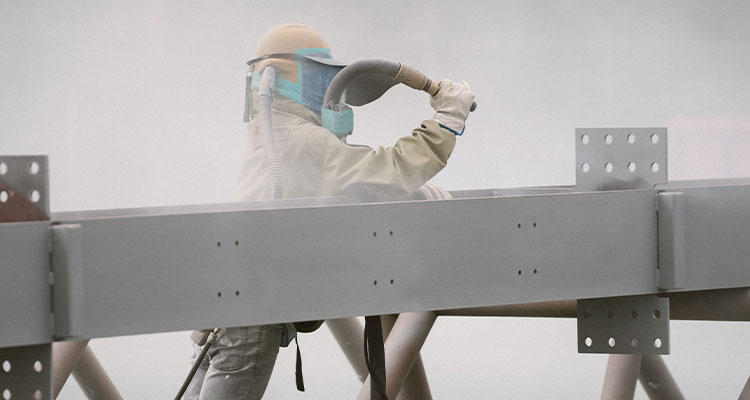 a worker applying intumescent paint to structural steelwork.
