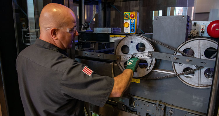 a man working on a machine with a chain drive system.