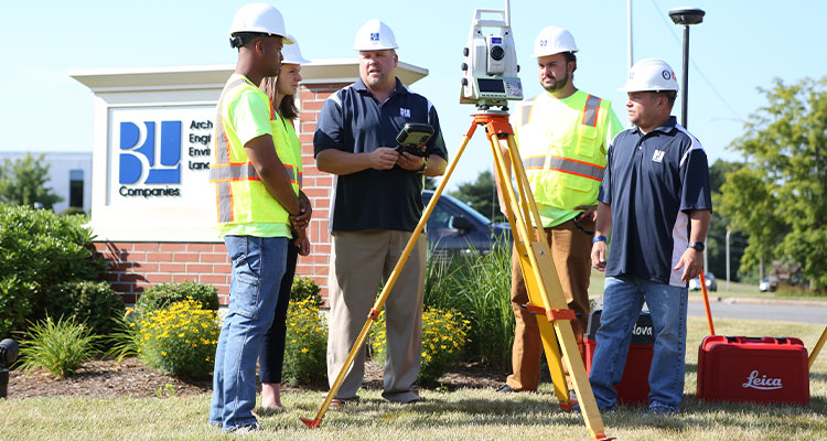 a group of surveyors using a total station, a specialized piece of equipment used in land surveying and construction