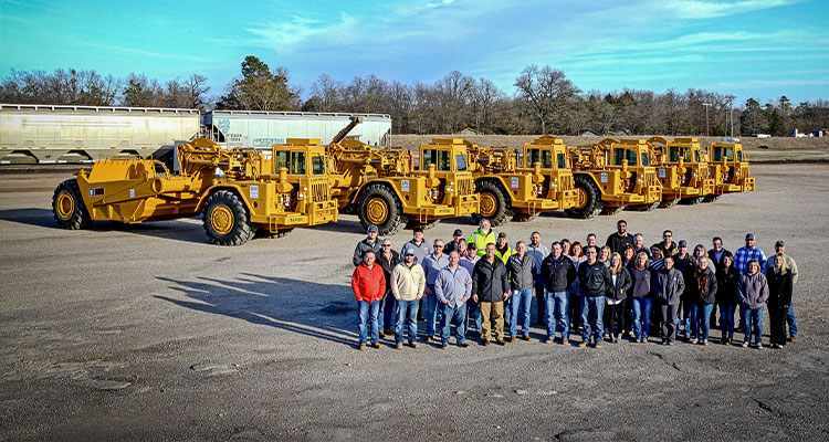 a group of people posing in front of several large construction vehicles