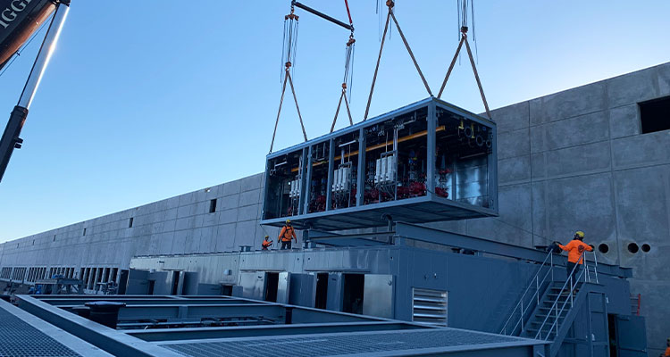 a large, pre-assembled module is being lowered into place by a crane