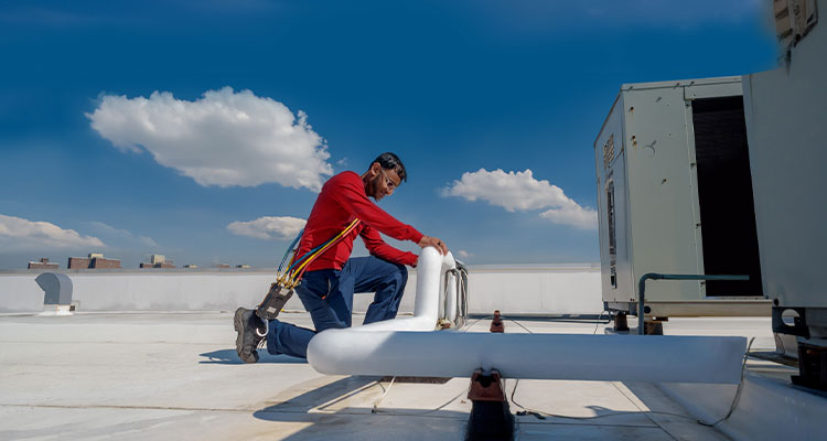 technician performing maintenance on a commercial rooftop HVAC unit