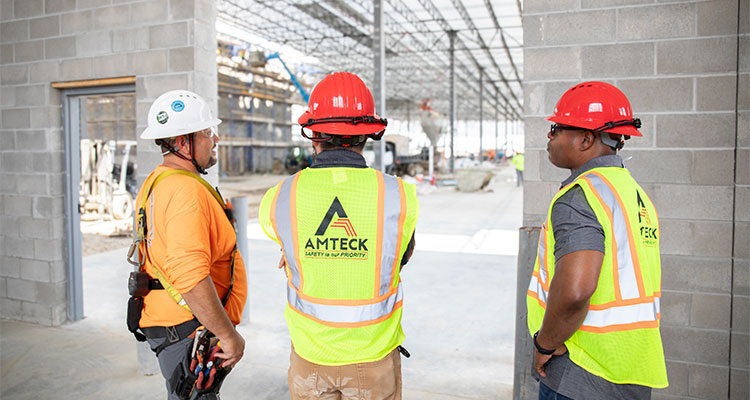 Amteck construction personnel on a job site wearing safety vests and hard hats